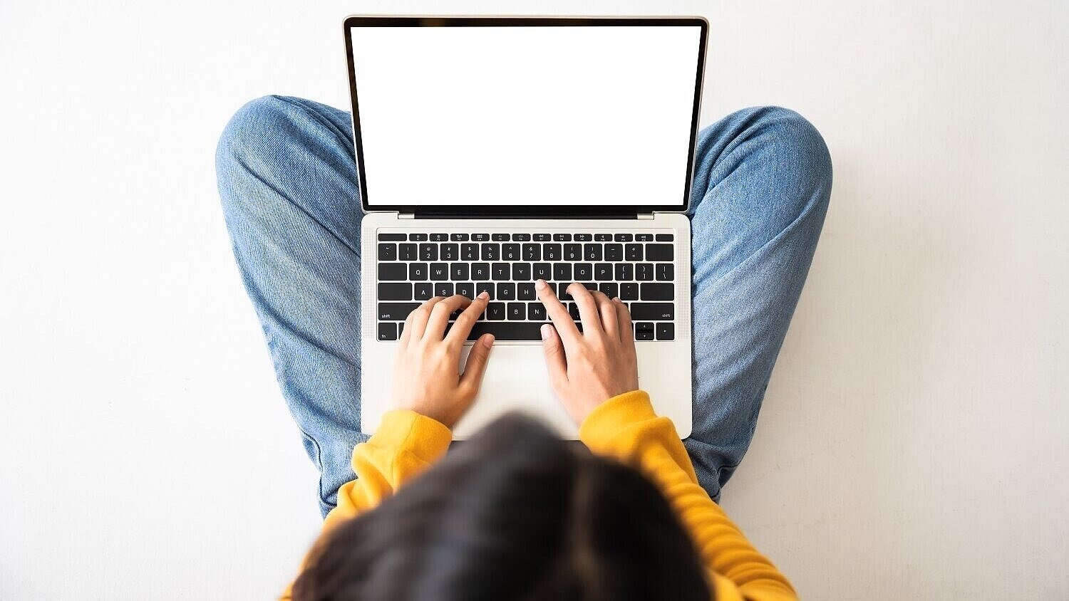 Frau sitzt auf dem Boden und hat einen Laptop auf dem Schoß