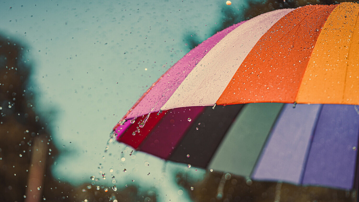 Bunter Regenbogen-Regenschirm bei Regenwetter